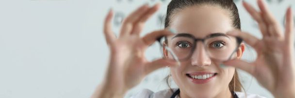 Retrato de mulher oftalmologista com gráfico de teste de olho no fundo. Optician fêmea experimentar óculos, nomeação no escritório olho. Checkup, conceito oftalmologista - Foto, Imagem