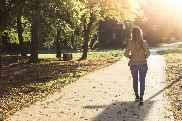 Nő sétál naplementekor. Boldog nő a parkban. - Fotó, kép