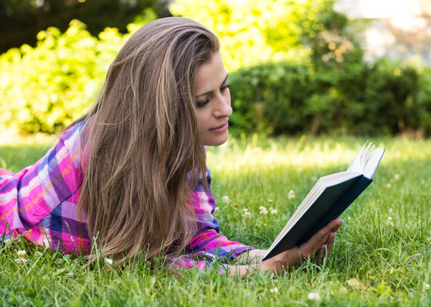 Piękna młoda kobieta czytająca książkę, w parku - Zdjęcie, obraz
