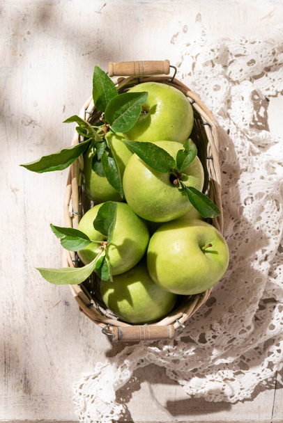 おばあちゃんスミスリンゴバスケットに。素朴な白の背景に新鮮な緑の果物 - 写真・画像