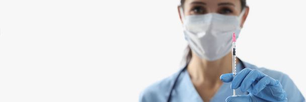 Kadın hemşirenin aşı sıvısıyla şırınga tutarken yüz maskesi taktığı yakın plan. Doktor ve aşıyı tehlikeli virüsten tedavi edin. Tıp, sağlık hizmeti kavramı - Fotoğraf, Görsel