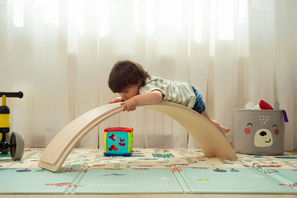 Kleines Mädchen spielt mit einem Balance Board, als wäre es eine Rutsche. - Foto, Bild