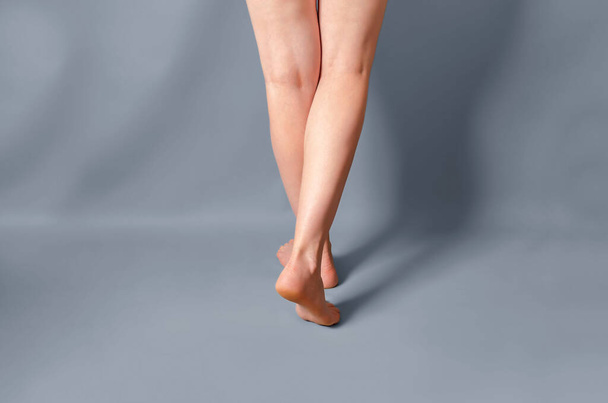 Slender female legs raised on toes on a light gray background. - Photo, Image