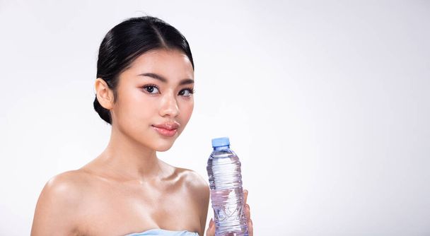 Portrait face shot of Young Asian 20s beautiful Woman open shoulder, look at camera, sweat fresh water on clean skin body. Happy female smile to empty label water bottle over white background isolated - Photo, Image