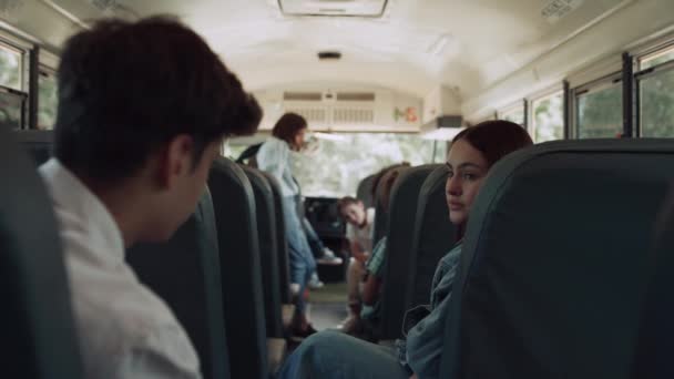 Többnemzetiségű osztálytársak beszélgetnek ülőhelyekről iskolabusz. A gondtalan gyerekek várják az iskolatársakat. Sötét hajú lány beszél egy indián fiúval. A belső közoktatási közlekedés kilátásai az utasokkal - Felvétel, videó