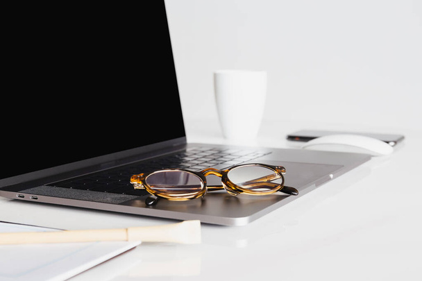 Laptop mit Brille und Kaffeetasse auf dem Tisch - Foto, Bild