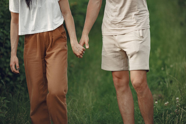 Couple in a field. Brunette in a white t-shirt. Pair walks. - Фото, изображение