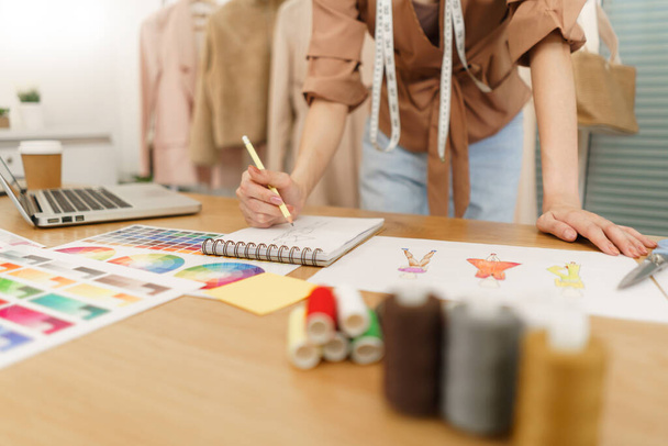 Modedesign-Konzept, asiatische Modedesignerin skizziert neue Kleidungskollektion im Atelier. - Foto, Bild