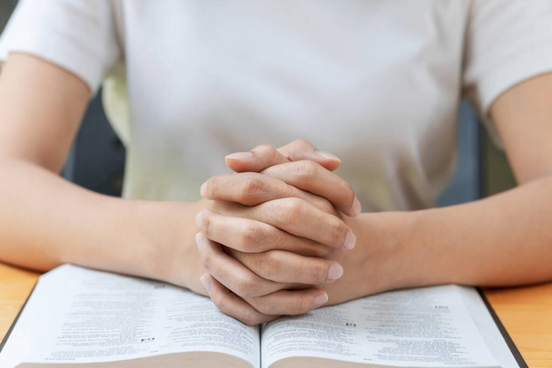 Concetto di preghiera e religione, mani cristiane femminili incrociate e leggere la Bibbia a pregare per la spiritualità. - Foto, immagini