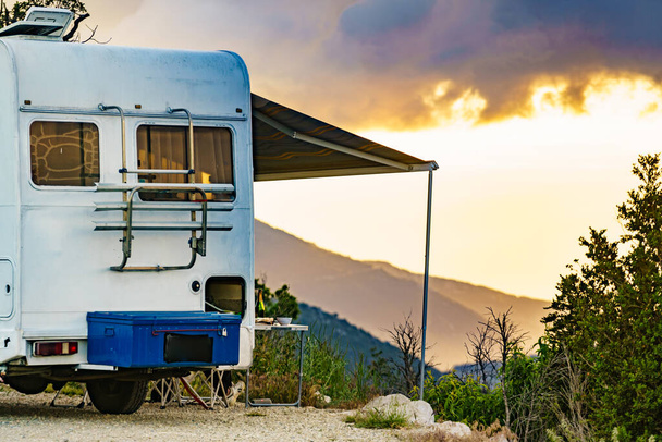 Camper vehicle with roll out awning and tourist table with chairs in french mountains. Camping on nature. Holidays and travel with motor home. - 写真・画像