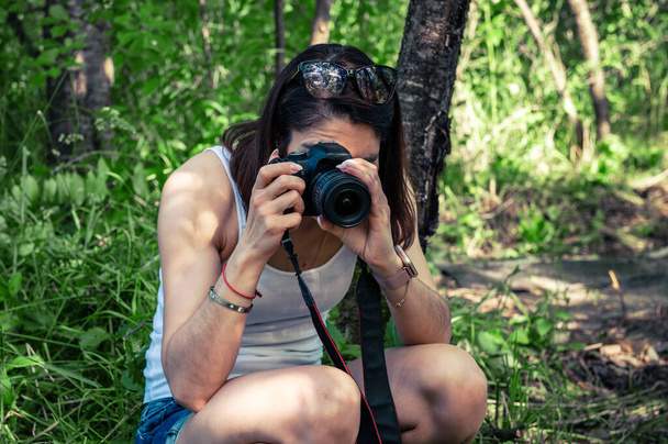 Mujer joven con una cámara tomando fotos al aire libre. Día mundial de la fotografía.  - Foto, imagen