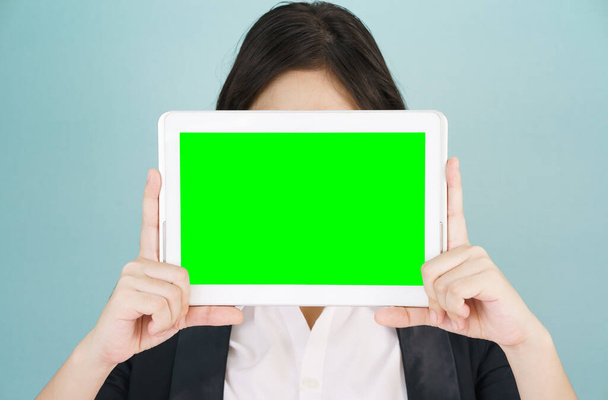 Young asian women in suit holding her digital tablet mock up standing against green background - Fotografie, Obrázek