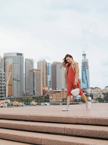Vrouw in de stad. Een dame in een rode jurk. Meisje loopt door de straten van Australië. - Foto, afbeelding
