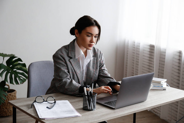 Young smart looking woman wearing glasses at the office, lawyer doing the paperwork. Portrait of female case studying at her workplace, dived deep into the work. Close up, copy space, background. - Photo, Image