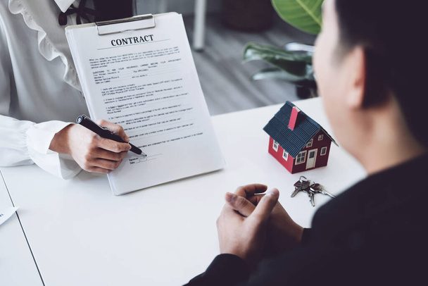 Guarantee, Mortgage, agreement, contract, Signing, Male client holding pen to reading agreement document to sign land loan with real estate agent or bank officer - 写真・画像