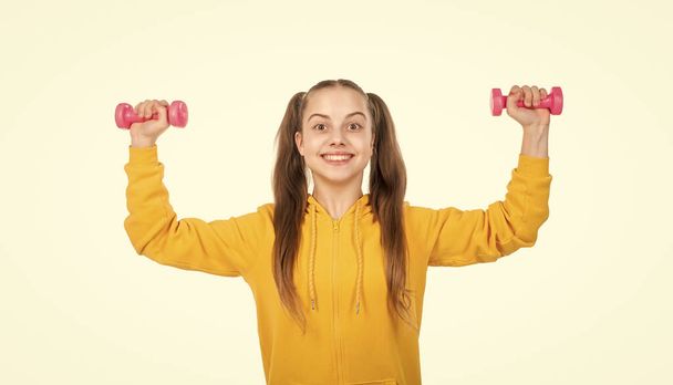 childhood health. healthy life. kid with sport equipment isolated on white. determination. demonstrating power. happy teen girl with dumbbell. sport and fitness. child training with barbells. - Фото, изображение