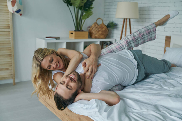 Cheerful young couple enjoying carefree morning while lying in bed together - Foto, immagini