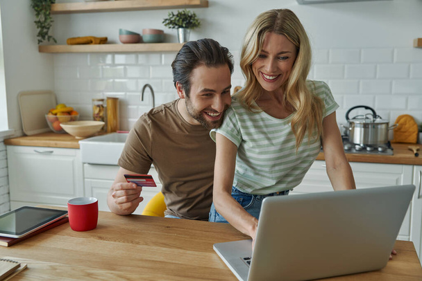 Happy young couple using credit card while shopping online from home - Valokuva, kuva