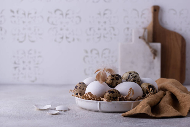 Bowl with chicken and quail raw eggs on light background - Fotó, kép