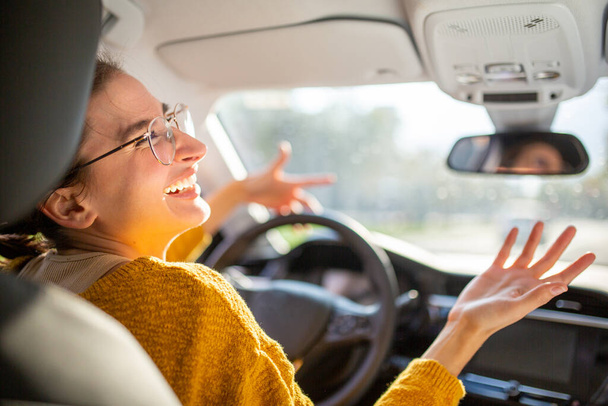 Портрет молодої стресової жінки водій сидить всередині її машини, дивлячись і жестикулюючи рукою, застрягши в пробці
. - Фото, зображення