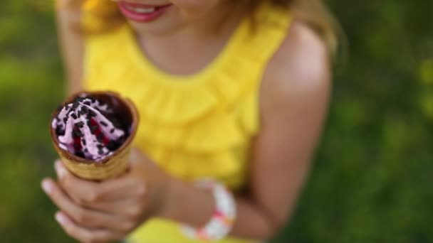Ragazza felice con l'apparecchio che mangia il cono gelato italiano sorridente mentre riposa nel parco durante la giornata estiva, bambino che si gode il gelato all'aperto, buone vacanze, estate - Filmati, video