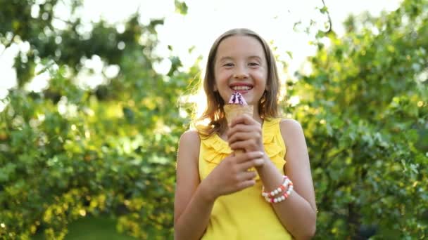 Boldog lány fogszabályzóval eszik olasz fagylalt kúp mosolyog, miközben pihen a parkban a nyári napon, gyermek élvezi a fagylaltot szabadban, boldog ünnepeket, nyáron - Felvétel, videó