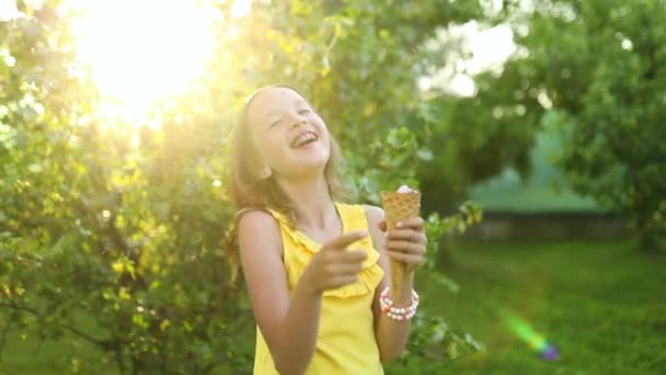Šťastná dívka s rovnátka jíst italskou zmrzlinu kužel s úsměvem při odpočinku v parku v letní den, dítě těší zmrzlinu venku, šťastné svátky, léto - Záběry, video
