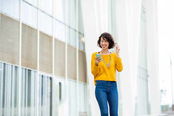 Carefree stylish young woman using smart phone outdoors in city - Photo, Image