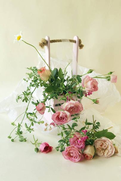 Fresh pink roses in a basket, flowers on a light background, the concept of a romantic greeting, a bridal bouquet, invitations, weddings, a card, packaging or sale in a flower shop - Photo, Image