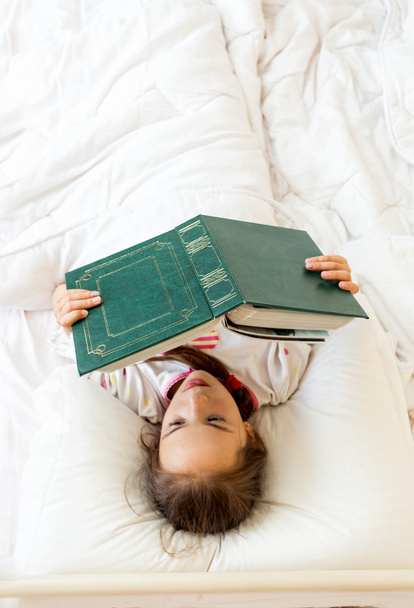 chytrá holčička, čtení velké staré knihy v posteli - Fotografie, Obrázek