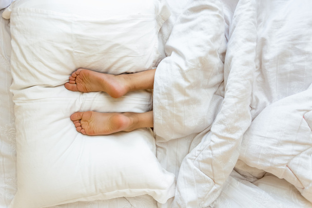 nogi leżącego na miękkie białe poduszki w łóżku - Zdjęcie, obraz