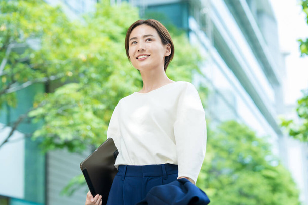 Eine lächelnde junge Frau steht im Büroviertel - Foto, Bild