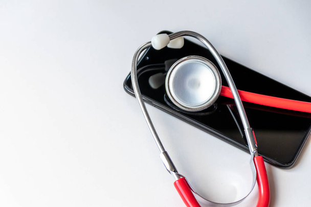 Estetoscópio vermelho no smartphone preto representa registros de saúde e registros digitais de pacientes com dispositivos móveis para médicos digitais e tratamento de diagnóstico digital com equipamentos e tecnologia modernos - Foto, Imagem