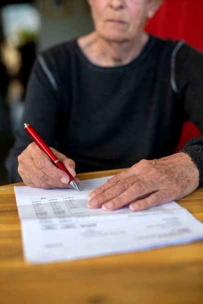 close-up of an older womans hand signing a paper - Fotó, kép