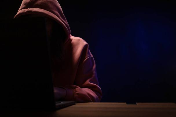 ラップトップコンピュータで働くハッカーの女性。暗室でのハッカー攻撃の背景 - 写真・画像