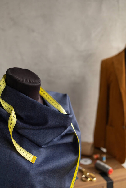Cloth fabric on tailor mannequin and tape measure. Concept of clothes atelier workplace - Foto, Imagen