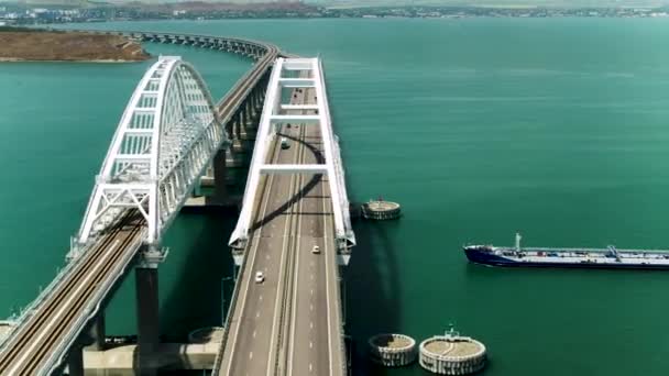 Un navire passe sous un grand pont avec des voitures en mouvement. Fusillade. Vue aérienne d'un pont et d'un navire à l'eau turquoise, effet time lapse - Séquence, vidéo
