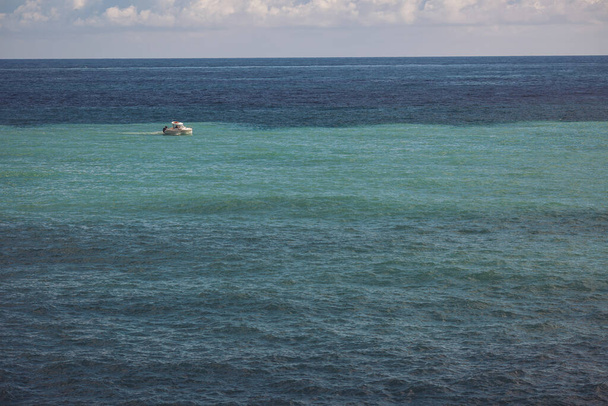 Motivos marinos. Barco de pesca en olas marinas. Vista de un barco blanco navegando en el mar azul. Vacaciones de primavera o de verano en Italia. Agua de mar azul turquesa. Día soleado. - Foto, imagen