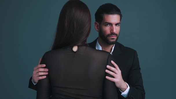 Takım elbiseli seksi, baştan çıkarıcı sakallı adam iki eliyle uzun saçlı kadınını sıkıca tutuyor. Gri arka plan stüdyo. Yüksek kalite 4k görüntü - Video, Çekim