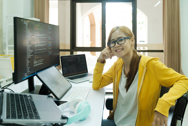 Genç programcı ya da bilişim uzmanı yaptığı işten memnun. Ofisinde çalışırken dizüstü bilgisayarda çalışan mutlu genç bir kadın.. - Fotoğraf, Görsel
