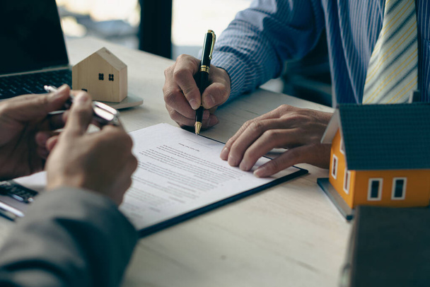 Immobilienmakler sprechen mit neuen Hauskäufern und bieten gute Zinssätze und berechnen Kunden für Hypothekenfinanzierungen, um bei der Entscheidung für ein Immobilienkonzept zu helfen. - Foto, Bild