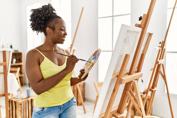 Genç Afrikalı Amerikalı sanatçı. Gülümsüyor. Sanat stüdyosunda mutlu çizimler.. - Fotoğraf, Görsel
