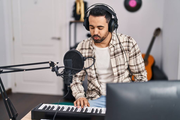 Young hispanic man musician singing song playing piano keyboard at music studio - Fotografie, Obrázek