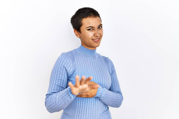 Young hispanic woman with short hair standing over isolated background disgusted expression, displeased and fearful doing disgust face because aversion reaction. with hands raised  - Photo, Image