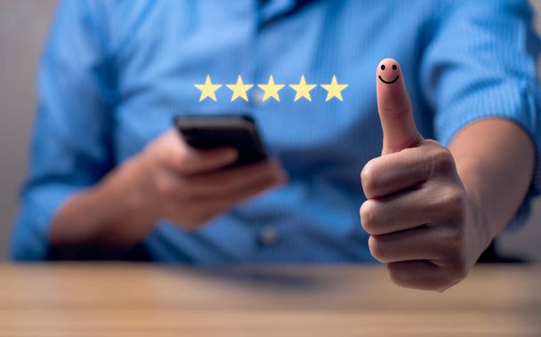 Customer satisfaction concept. Hand with thumb up Positive emotion smiley face icon and five star with copy space. 5 star satisfaction, Excellent business rating experience - 写真・画像