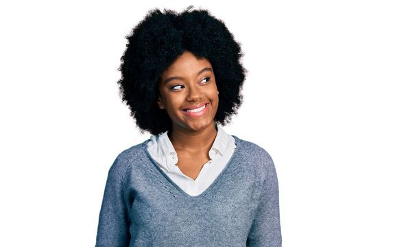 Jeune femme afro-américaine portant des vêtements de travail regardant de côté avec le sourire sur le visage, expression naturelle. riant confiant.  - Photo, image