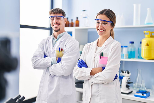 Молодий чоловік і жінка-вчені робітники, що стоять на руках, схрестили жест у лабораторії
 - Фото, зображення