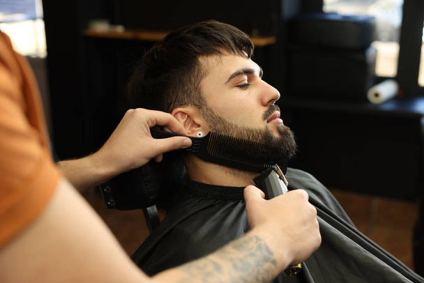 Professional hairdresser working with bearded client in barbershop - Zdjęcie, obraz