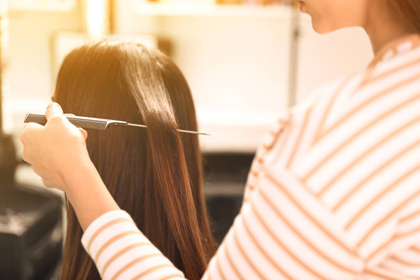 Professional hairdresser working with client in beauty salon, closeup - 写真・画像
