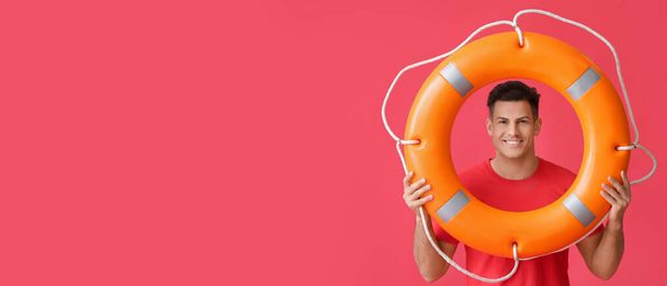 Beach rescuer holding lifebuoy on red background with space for text - Valokuva, kuva
